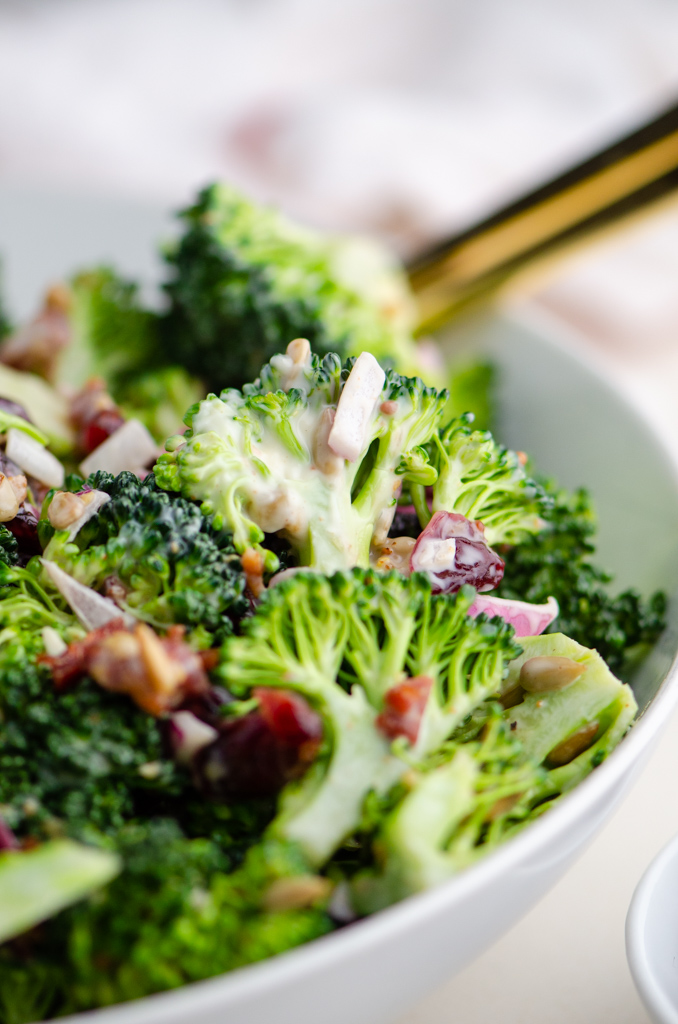 Close up side photo of broccoli salad in a white bowl. 