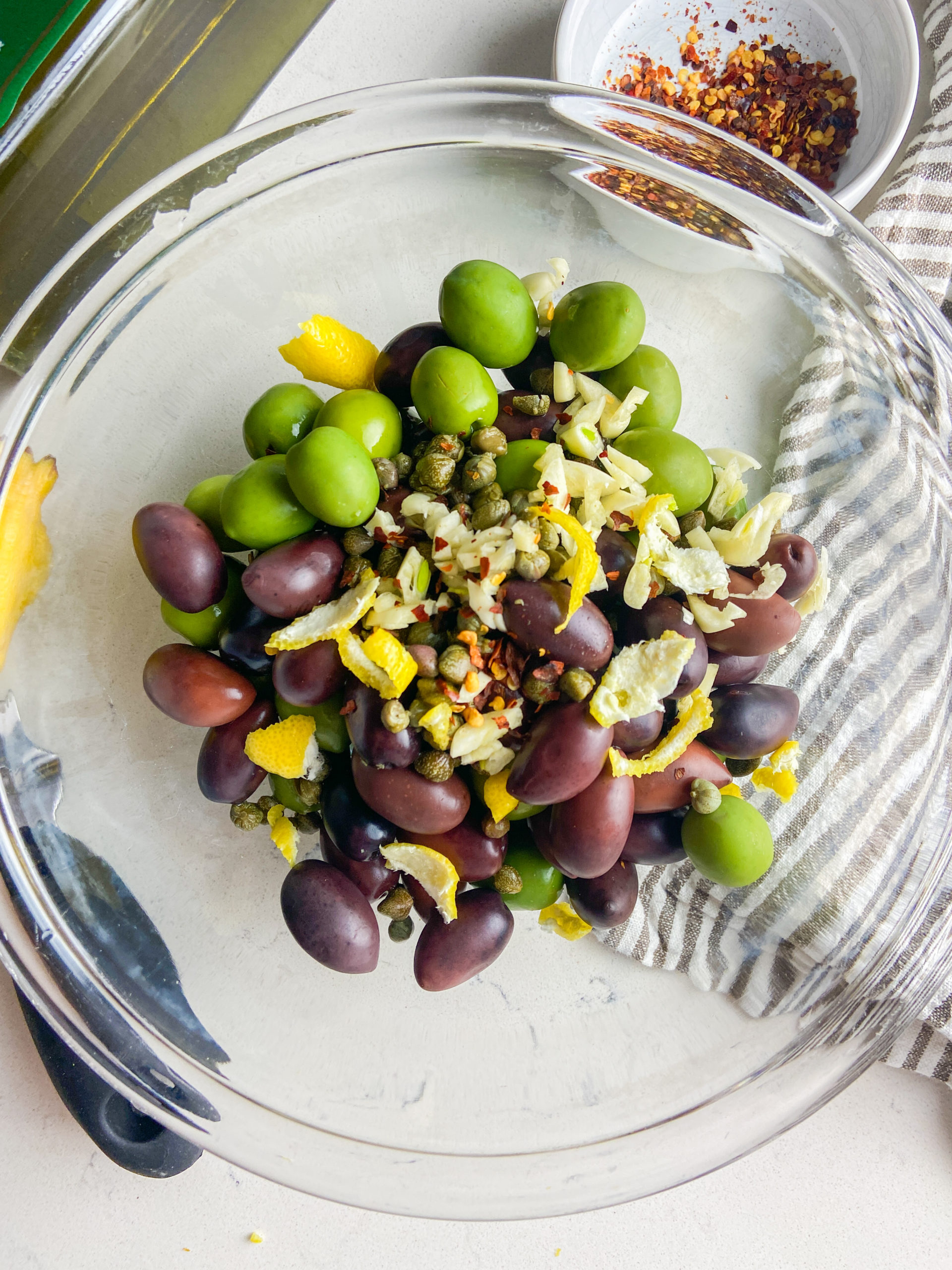 All ingredients for marinated olives in a clear bowl. 