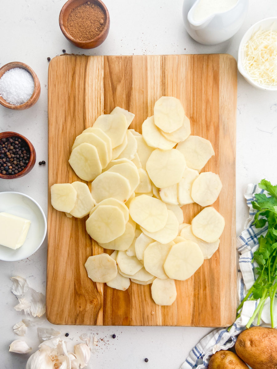 thinly sliced potatoes on a cutting board. 