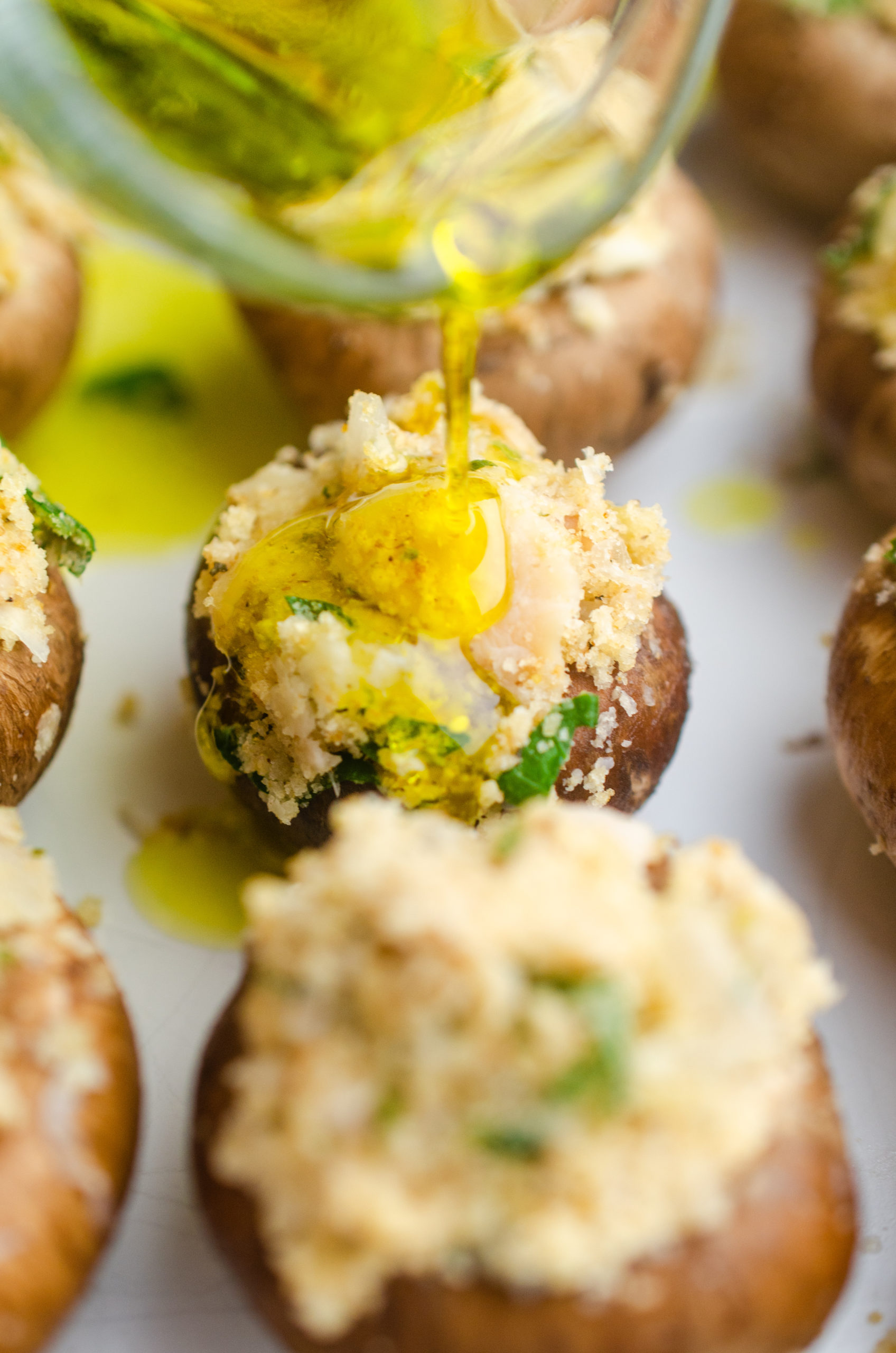Drizzling olive oil over stuffed mushrooms. 
