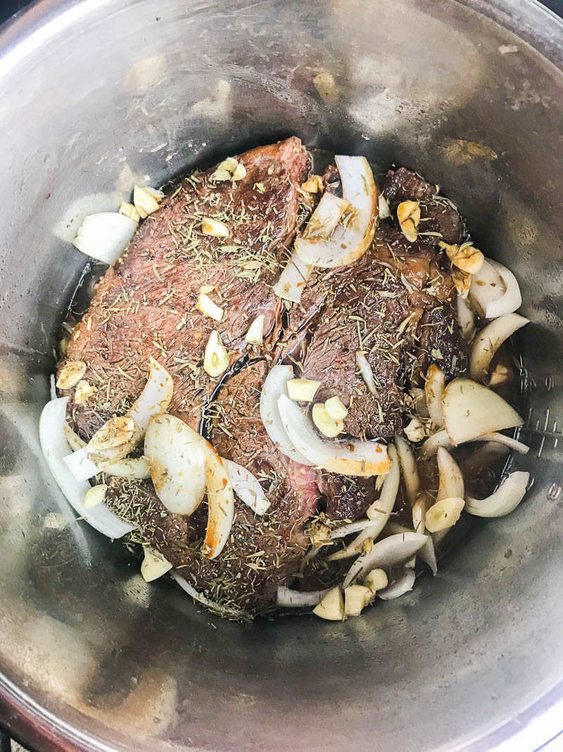 Chuck roast in instant pot with onions, garlic, and beef broth