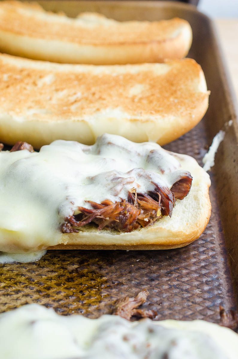 Melted cheese on top of shredded beef sandwich