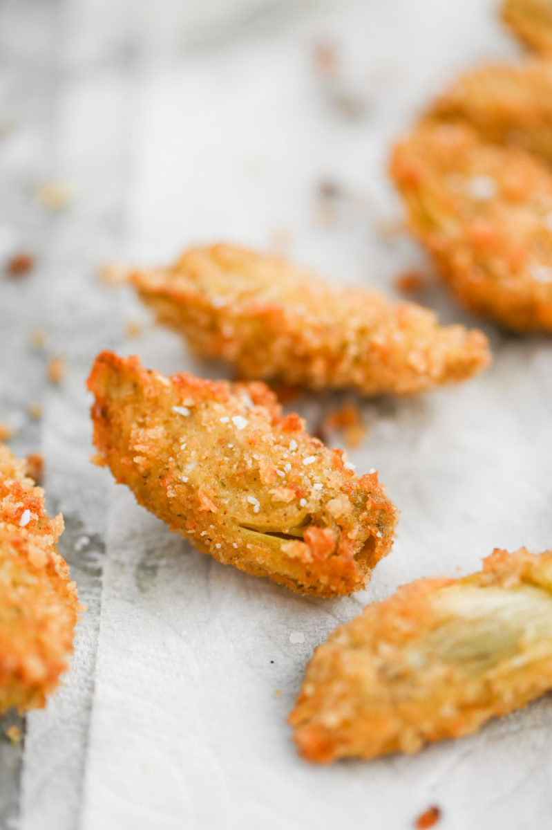 Fried Artichoke Hearts on paper towel sprinkled with salt. 