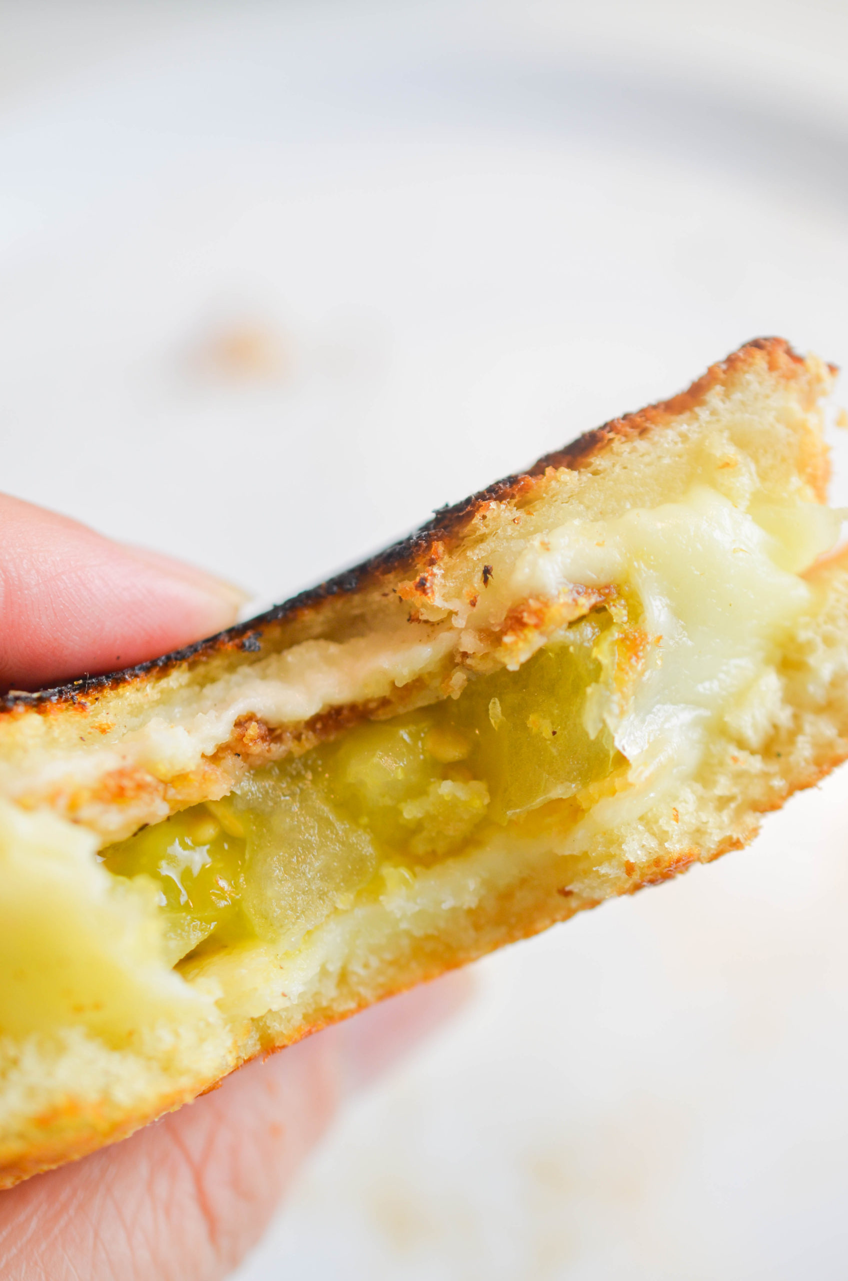 The inside of a fried green tomato grilled cheese. 