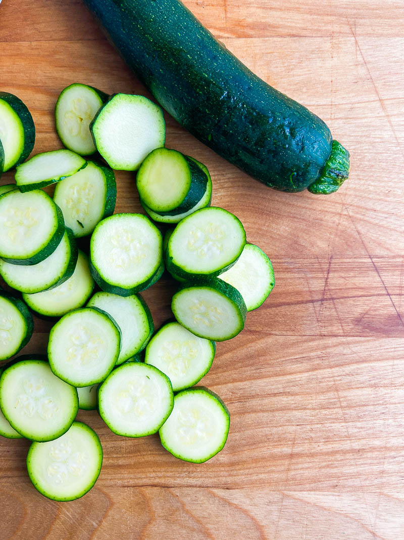 sliced zucchini rounds on a wooden cutting board. 