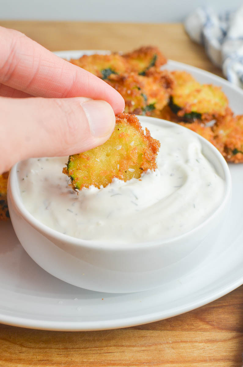 Dipping fried zucchini in creamy ranch dip. 
