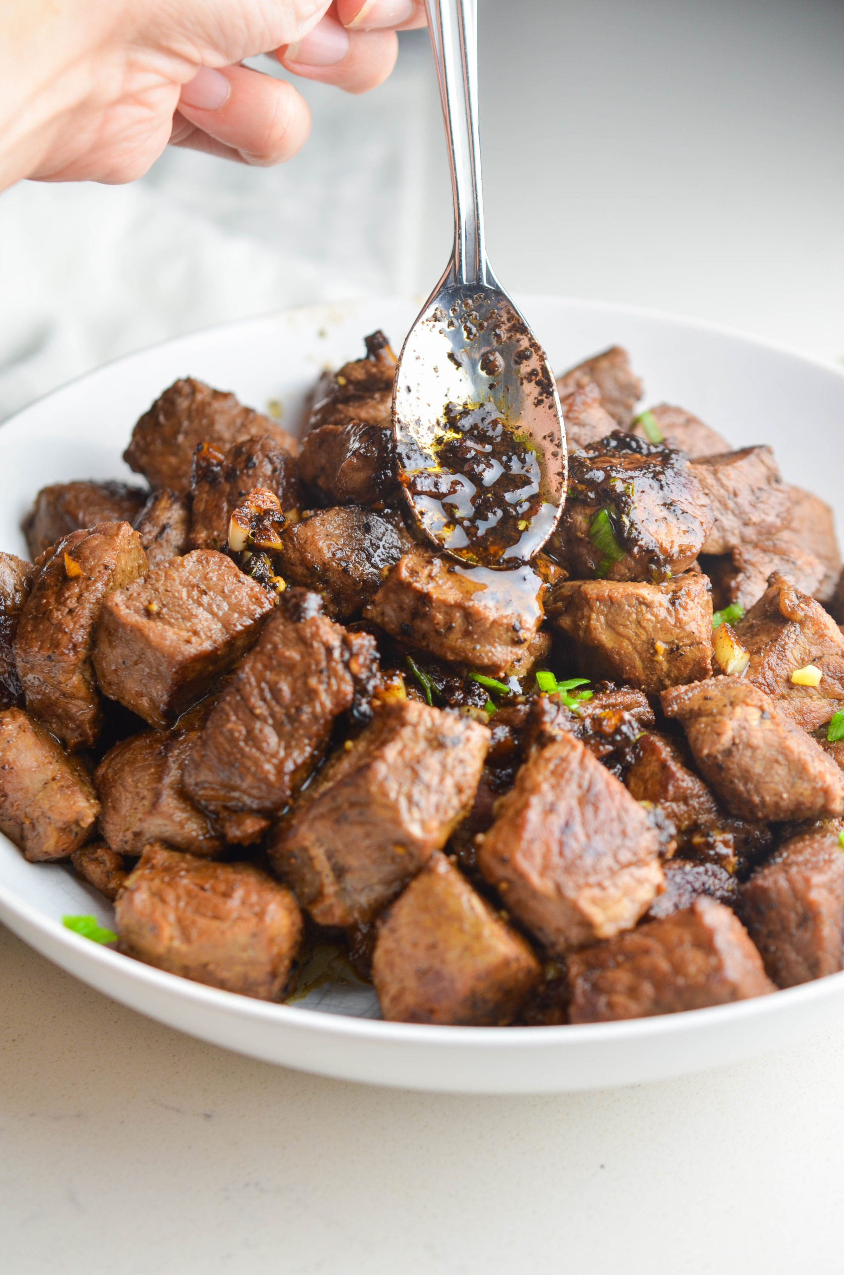 Drizzling garlic butter over steak bites. 