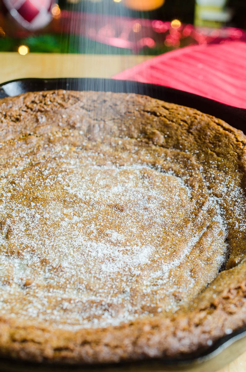 Sprinkling sugar on gingersnap skillet cookie.