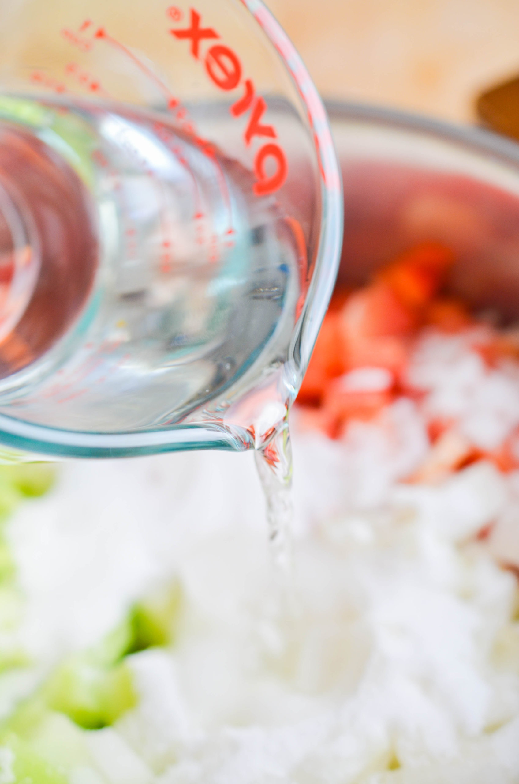 Pouring vinegar into a sauce pan filled with relish ingredients. 