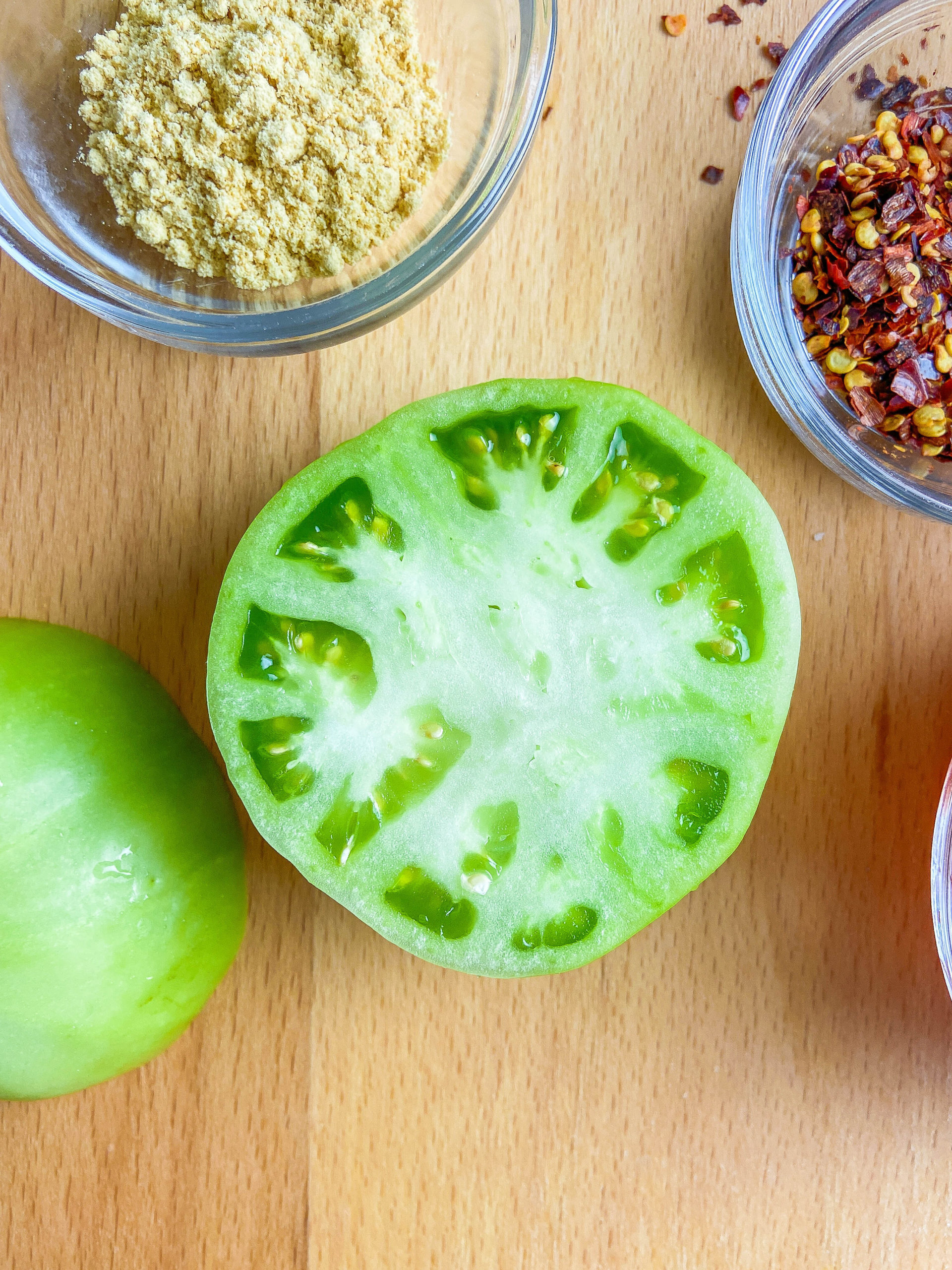 Halved green tomato on a wooden cutting board