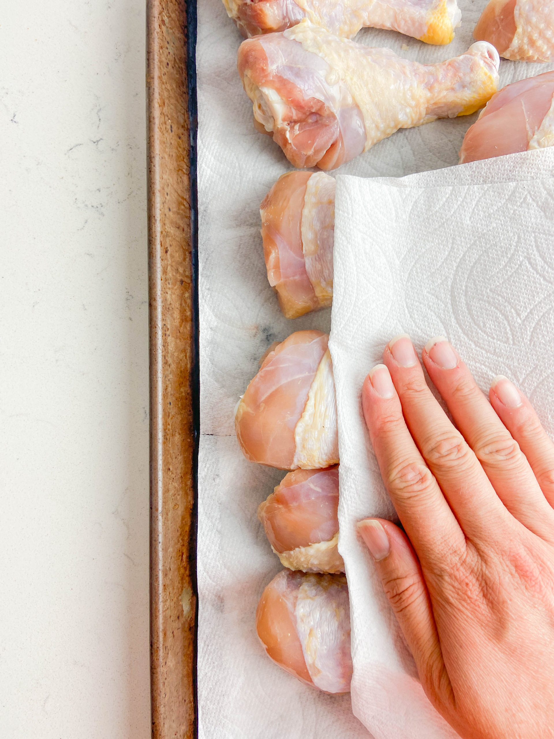 Patting chicken legs dry with a paper towel. 