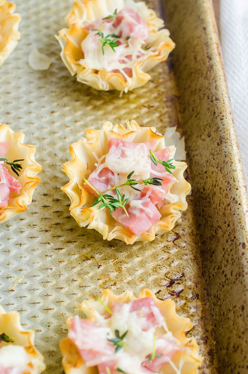 Ham and Gruyere in phyllo pastry cups on a baking sheet.