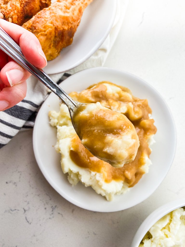 A spoonful of mashed potatoes and gravy. 