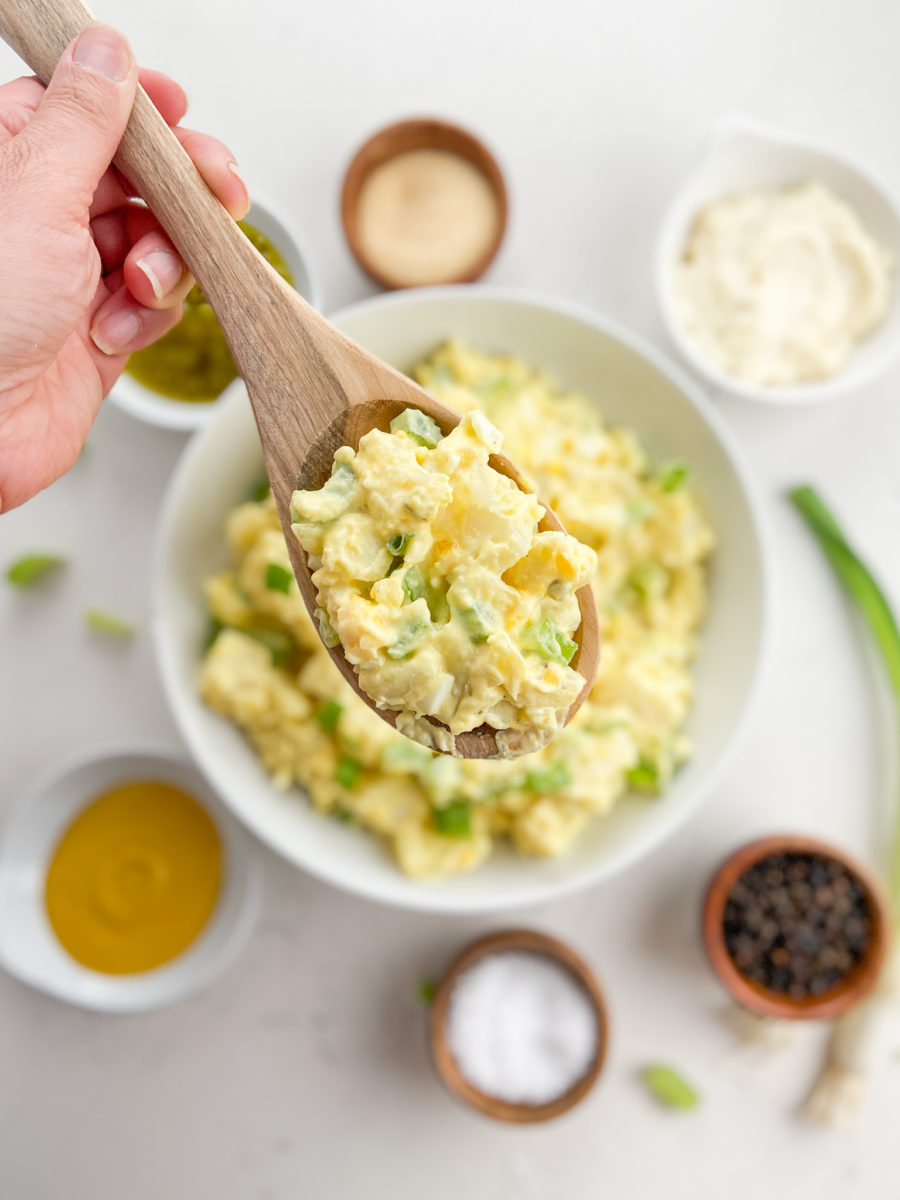 Wooden spoon with scoop of potato salad. 