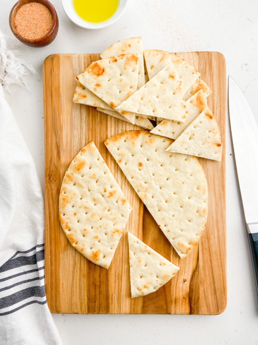 Pita cut into triangles on cutting board. 