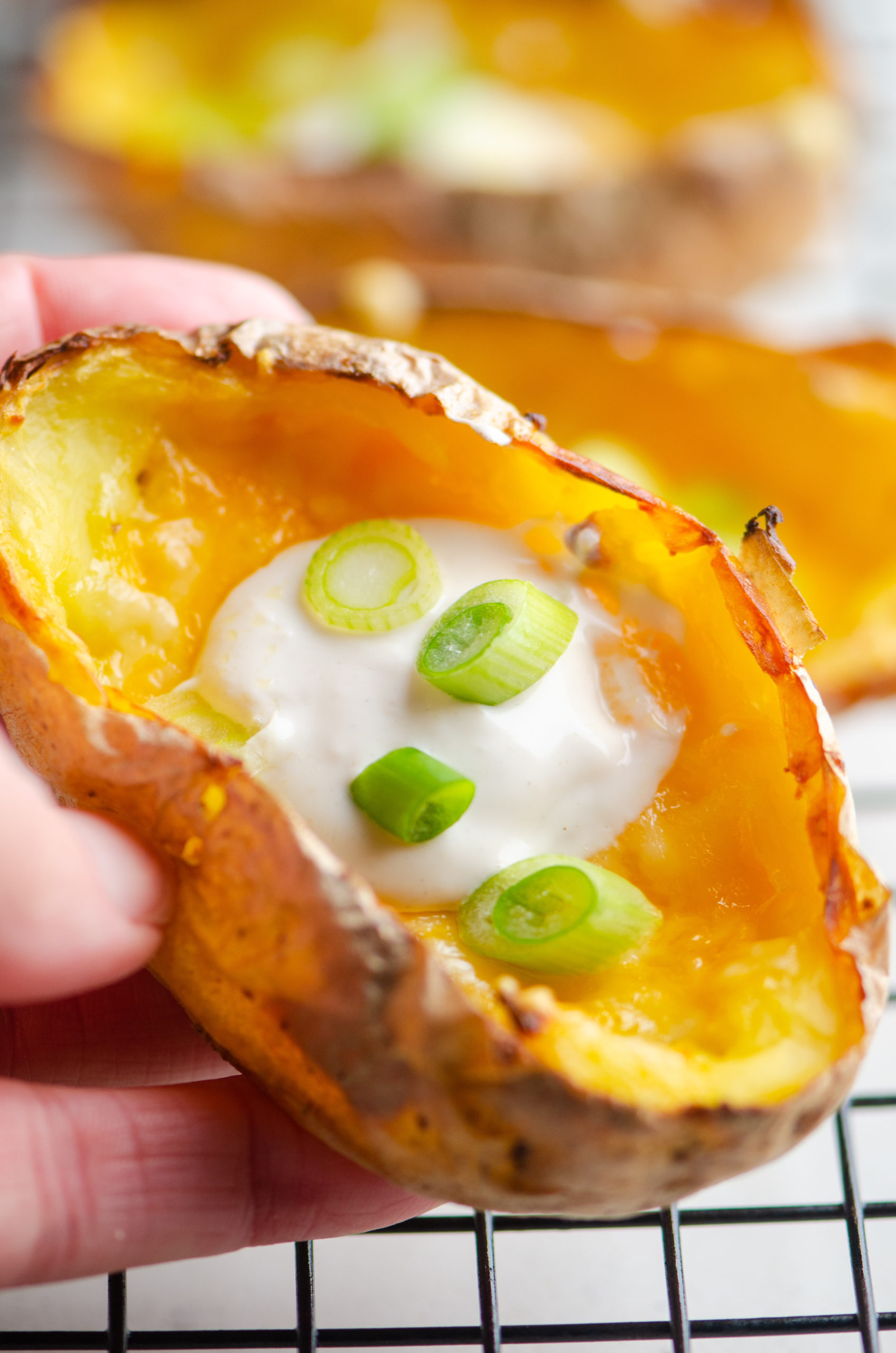 Close up photo of potato skin with sour cream and green onions. 