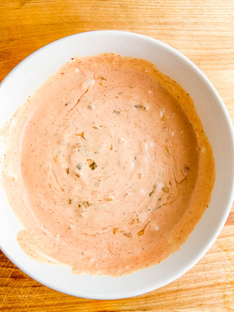 Thousand Island Dressing in a white bowl on wooden cutting board. 