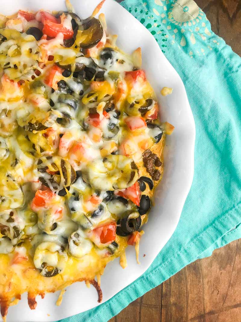 Overhead photo of hot nacho dip in a white casserole dish with a teal napkin.