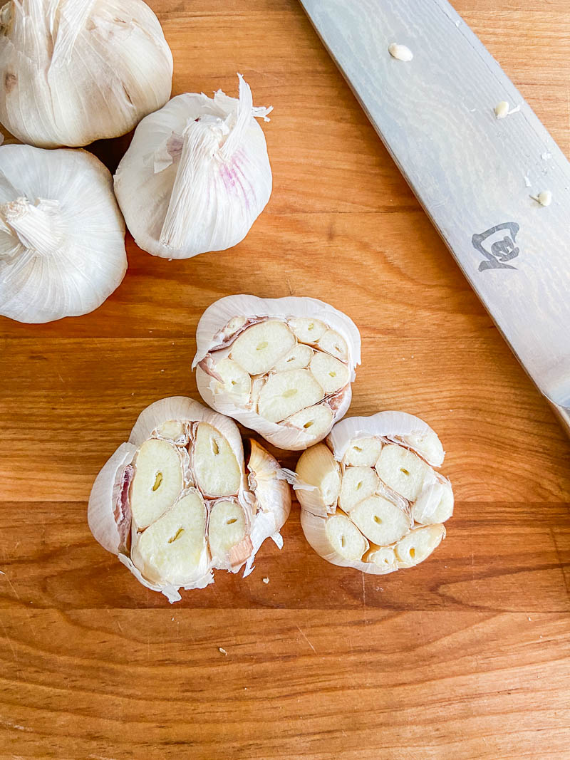 Raw garlic heads on a cutting board. 