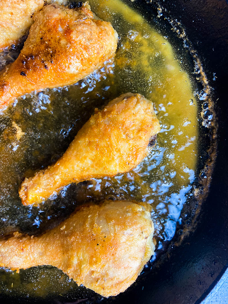 Fried chicken frying in a black cast iron skillet. 