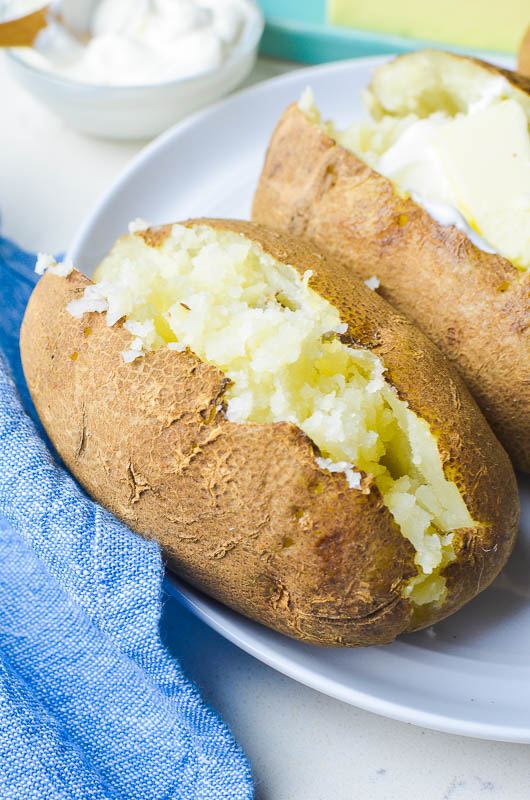 Plain baked potato on a white plate with blue napkin 