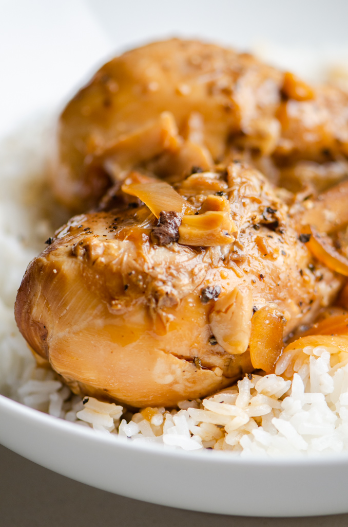 Close up side photo of chicken adobo in a bowl with rice. 