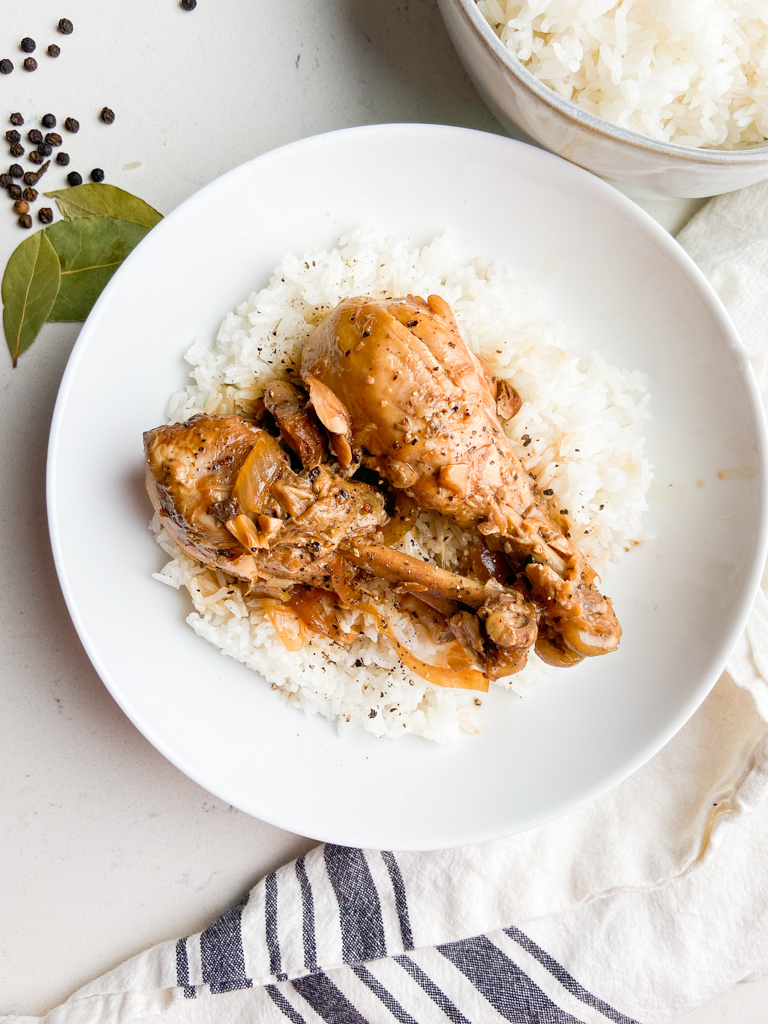 Overhead photo of chicken adobo in a white bowl with rice. 