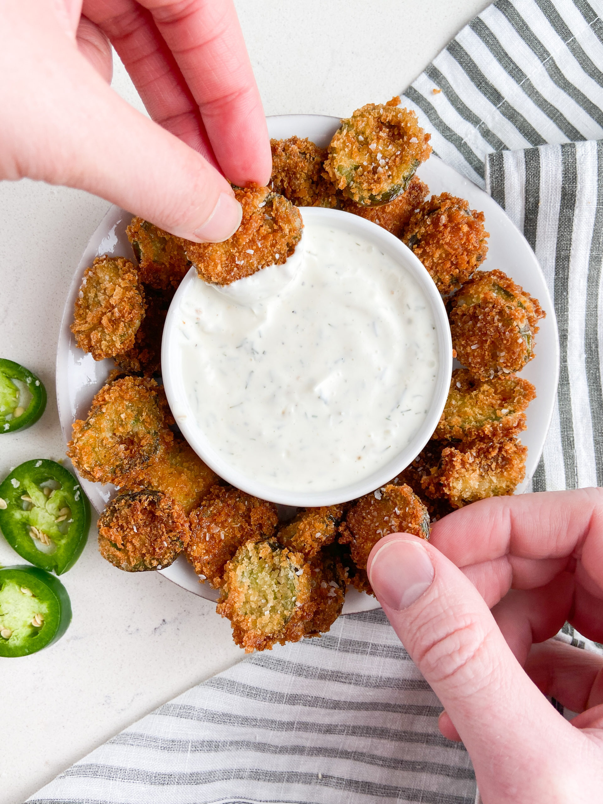 Two hands dipping jalapeno bites in ranch dip. Overhead photo. 