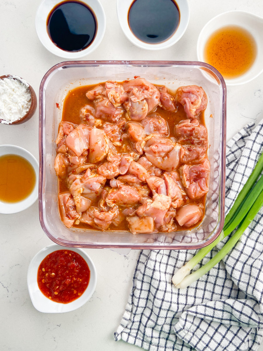 chicken marinating in plastic dish. 