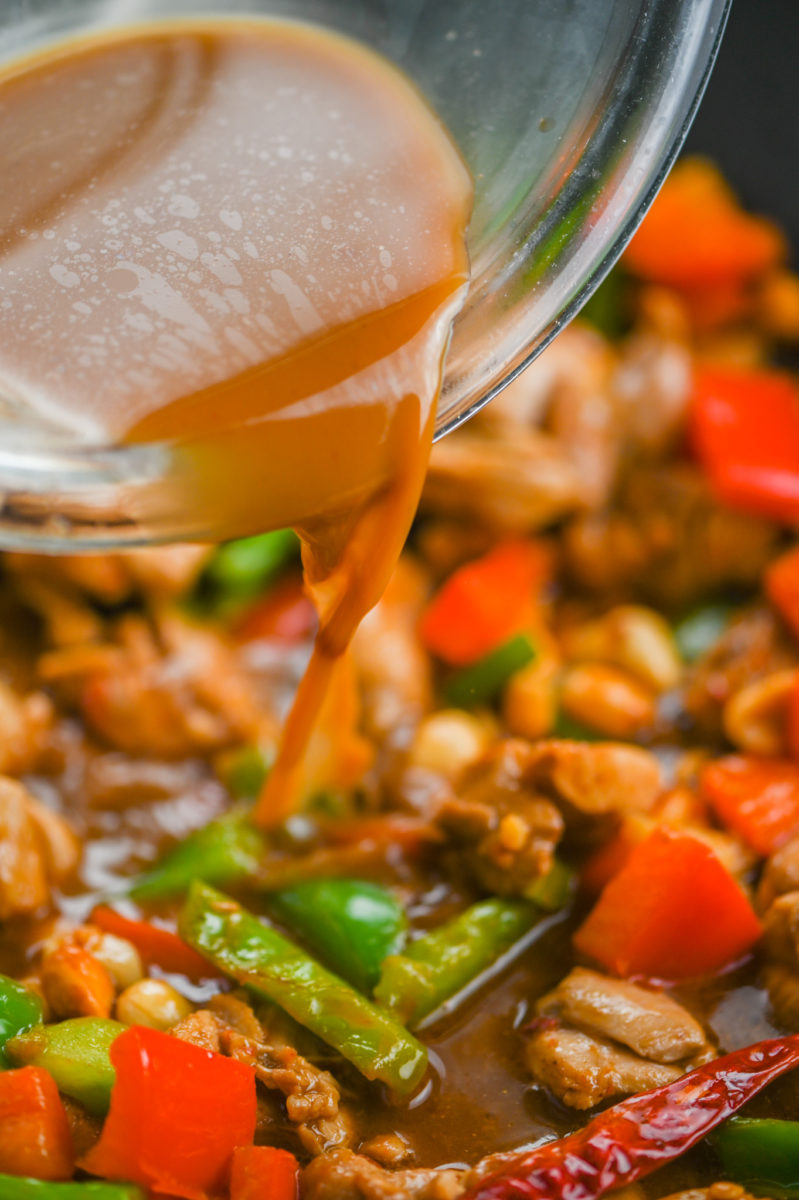 Pouring kung pao sauce over stir-fry.