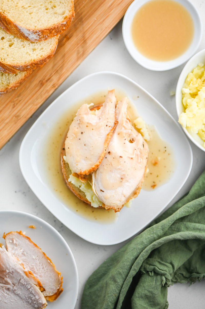 Open faced turkey sandwich on white plate.