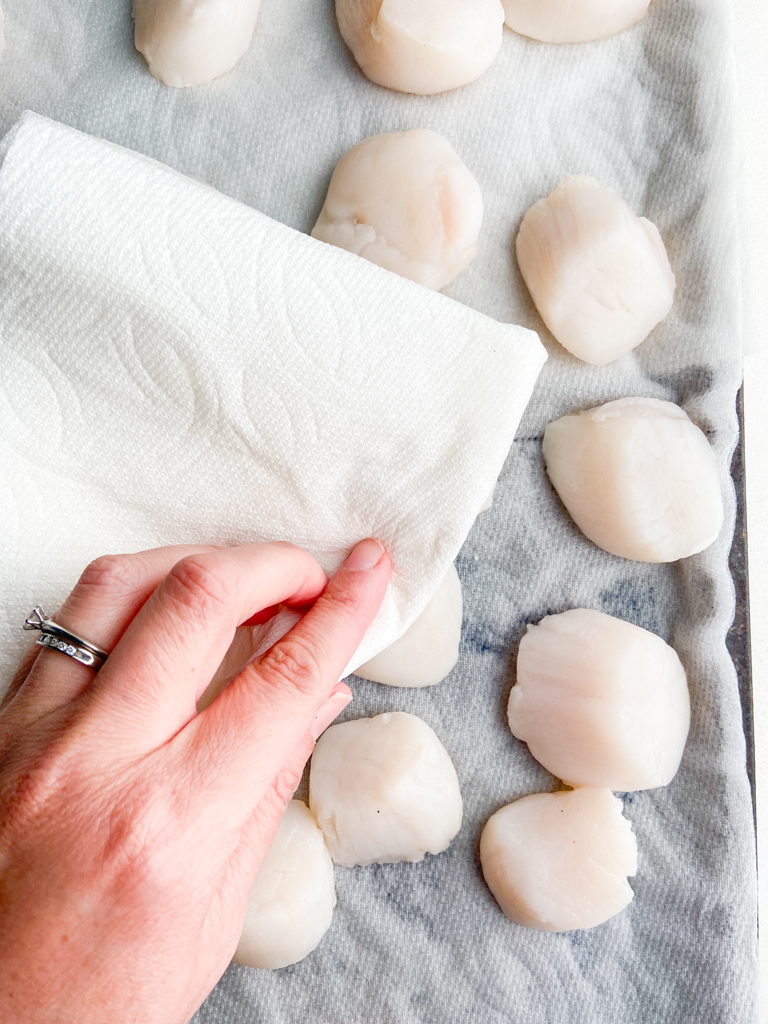 Patting scallops dry with a paper towel. 