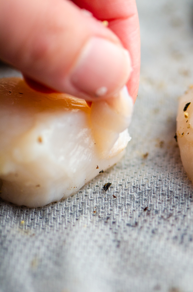 Removing side muscle from scallops. 