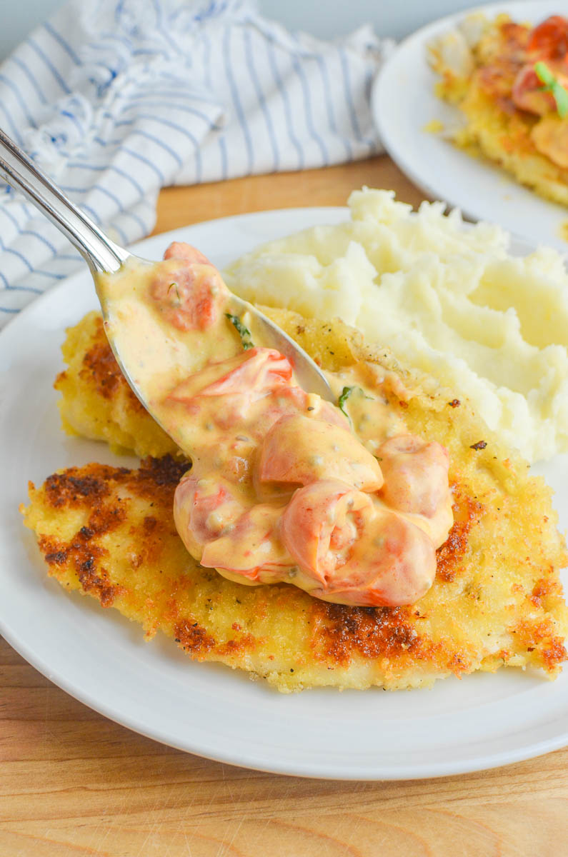 Spooning Tomato Basil Cream Sauce onto tilapia. 