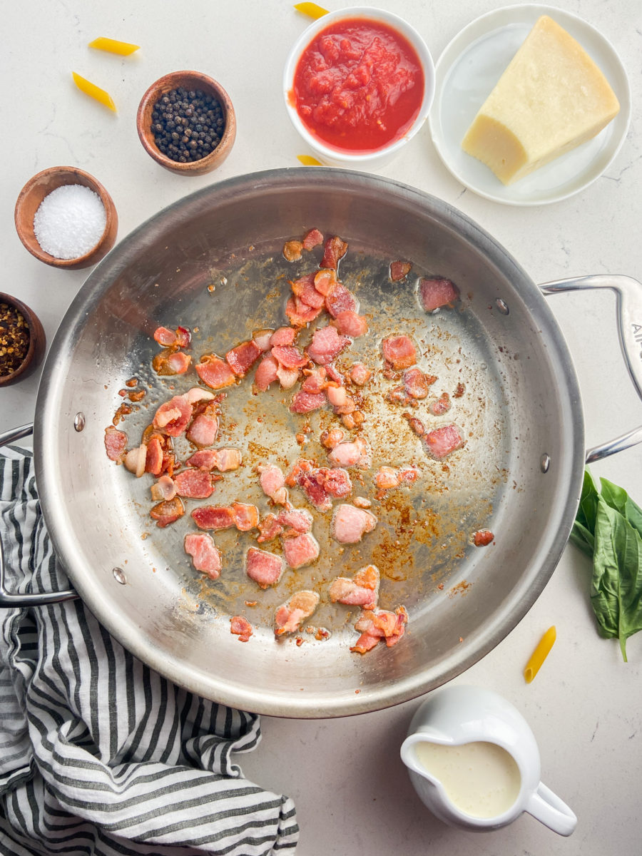 Cooking bacon pieces in stainless steel pan.