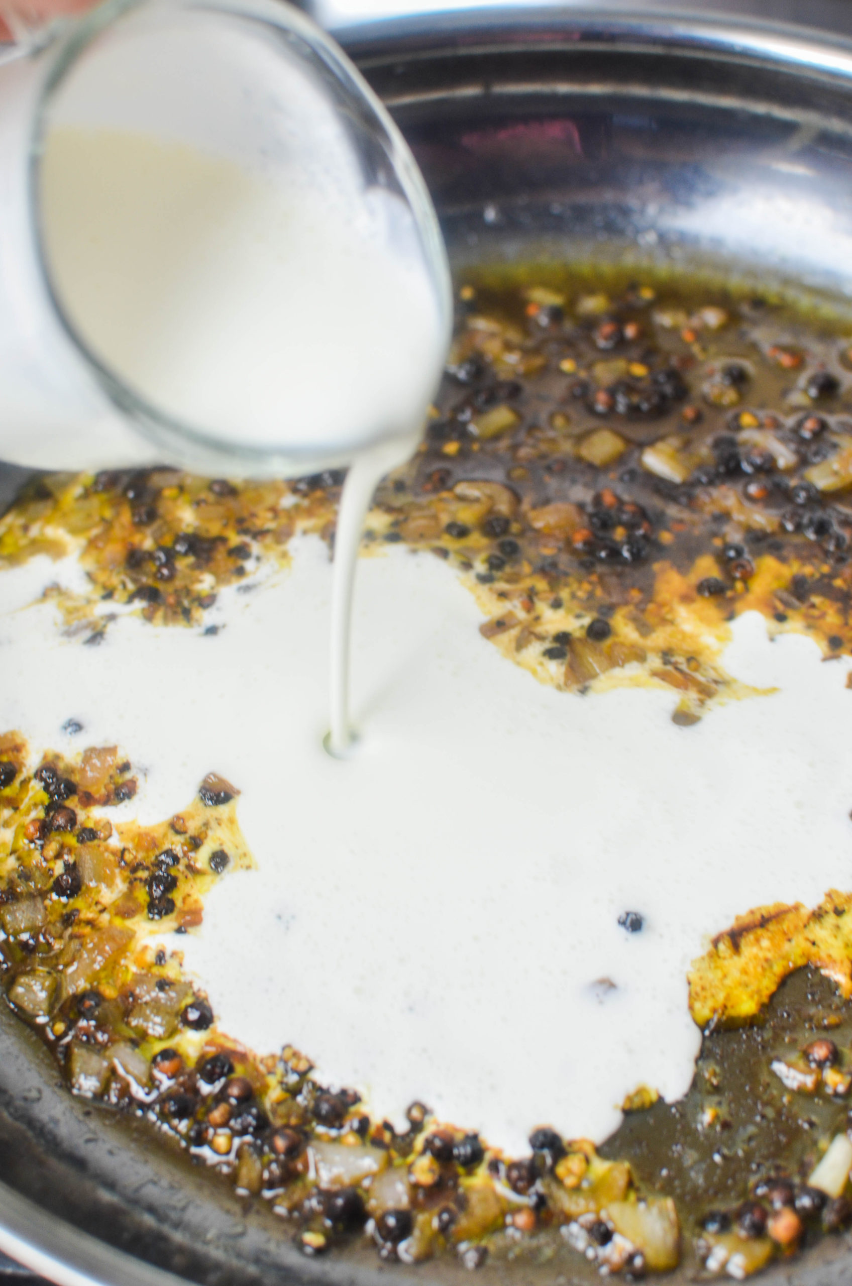 Pouring cream into a skillet. 