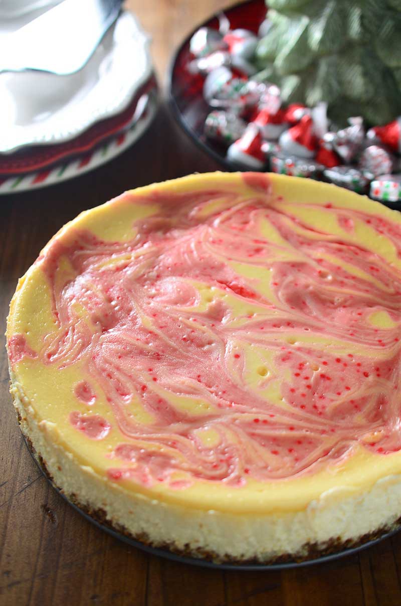 Luscious eggnog cheesecake is swirled with melted Hershey's Candy Cane Kisses in this Peppermint Eggnog Cheesecake making it a perfect holiday treat!