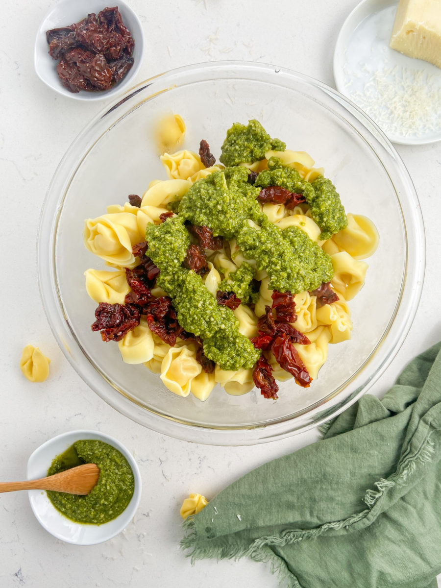 Tortellini, sun-dried tomatoes and pesto in a glass bowl. 