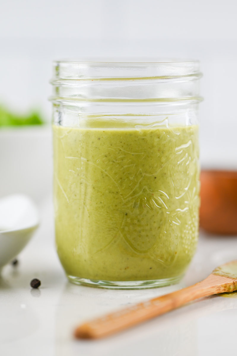 Pesto vinaigrette in a mason jar with a wooden spoon. 