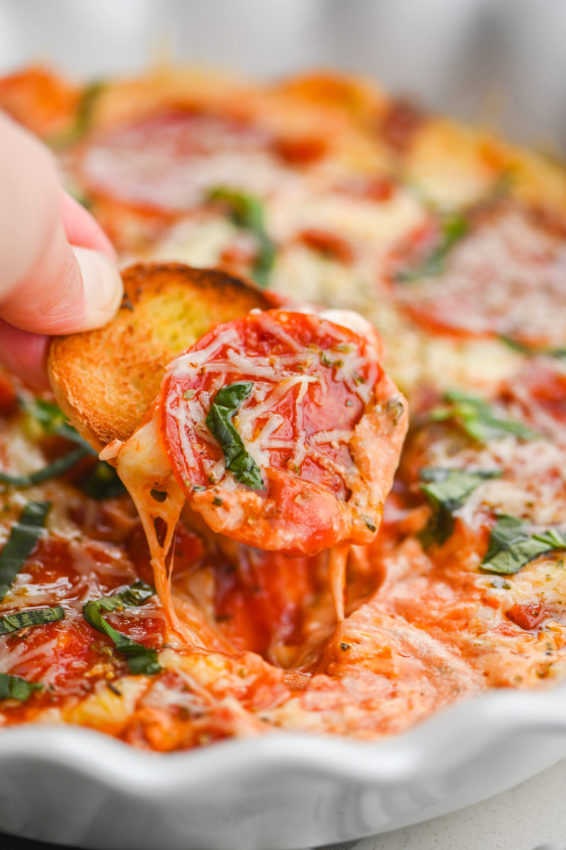 Scooping up pizza dip with sliced baguette. 