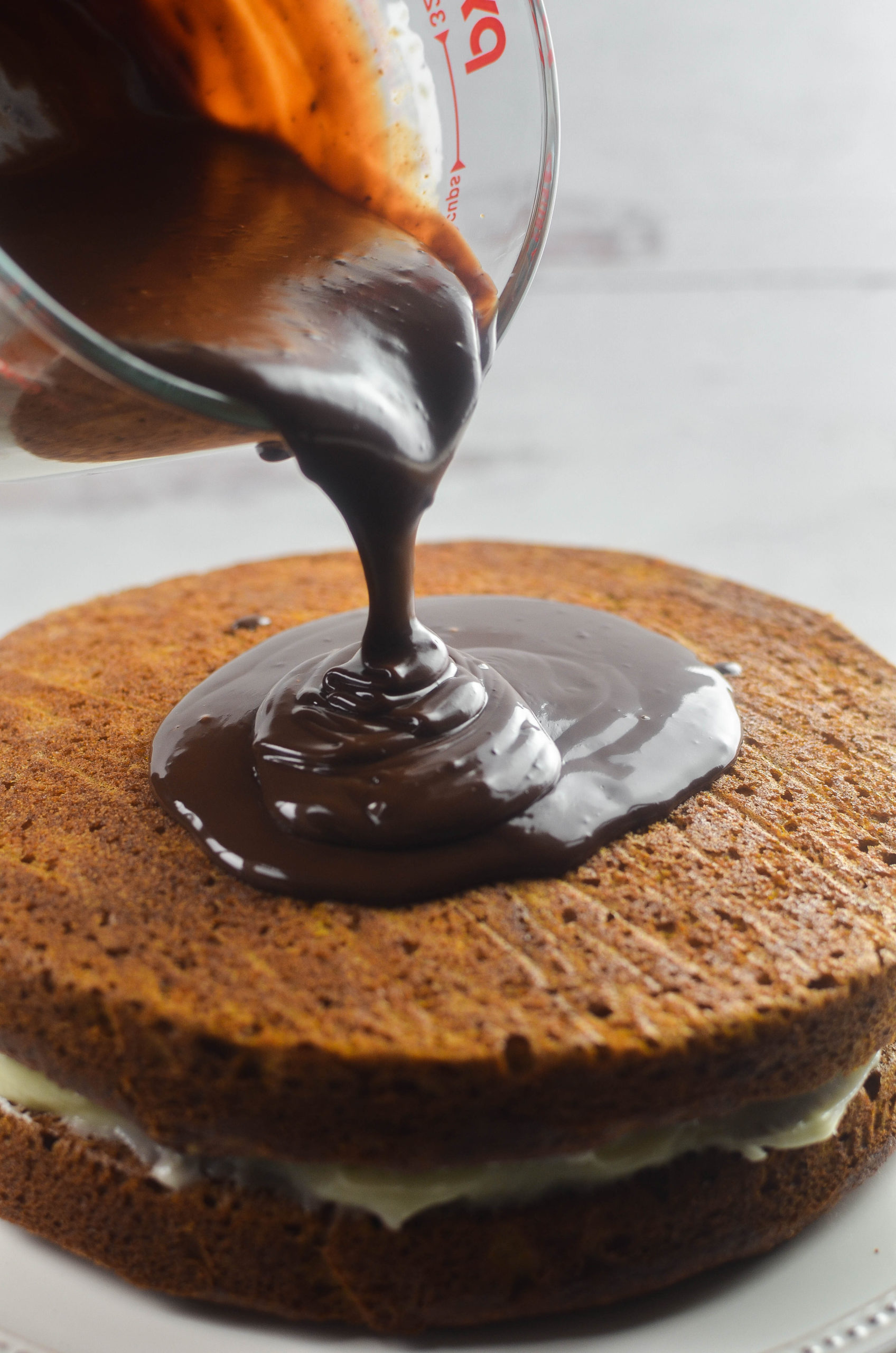 Pouring ganache over top of pumpkin cake. 