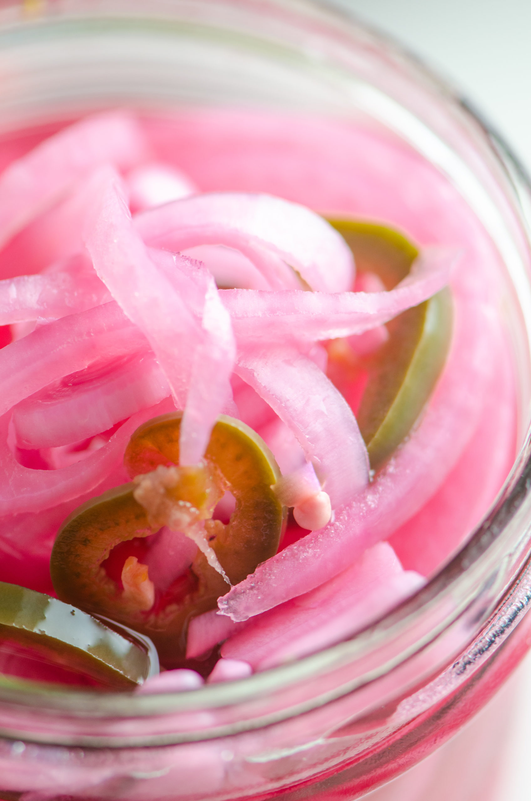 Close up photo of quick pickled red onions in a glass jar. 