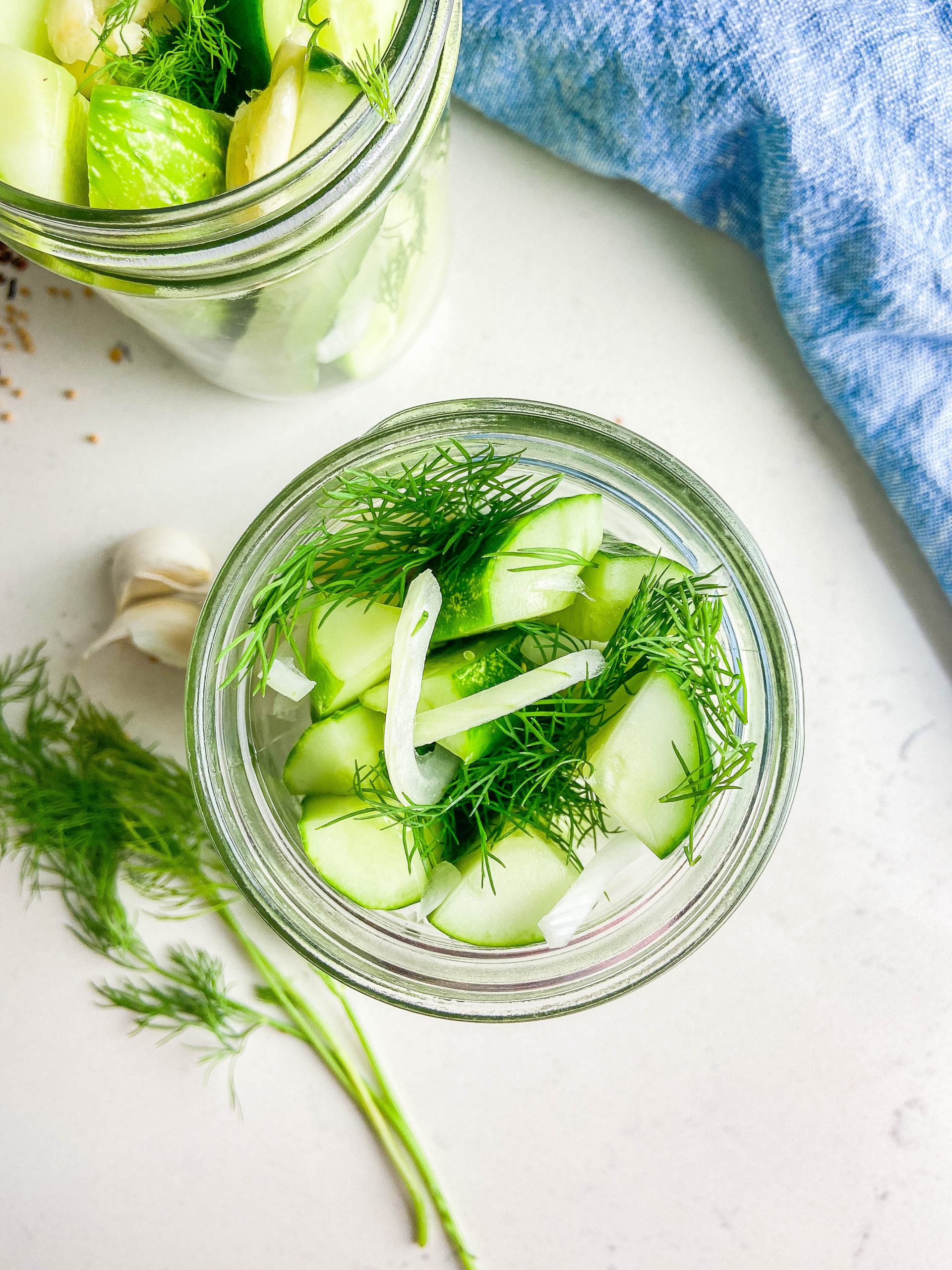 Overhead photo of Cucumbers, onions and dill in a glass jar. 