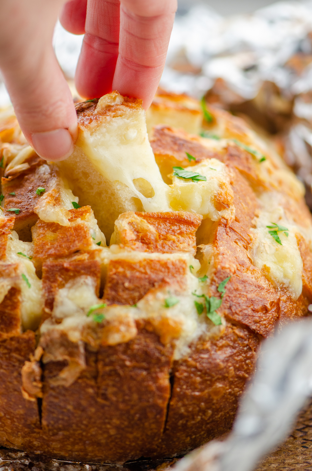 A hand pulling a cube of pull apart bread. 