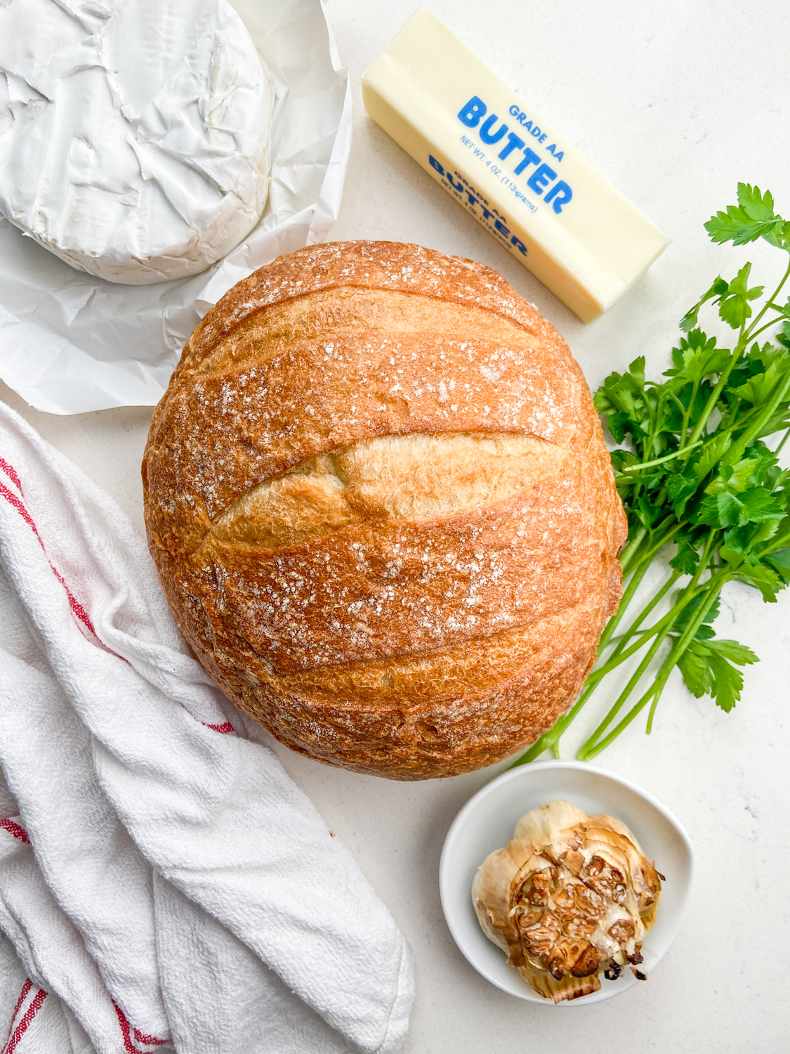 Ingredients for roasted garlic and brie pull apart bread on white background. 