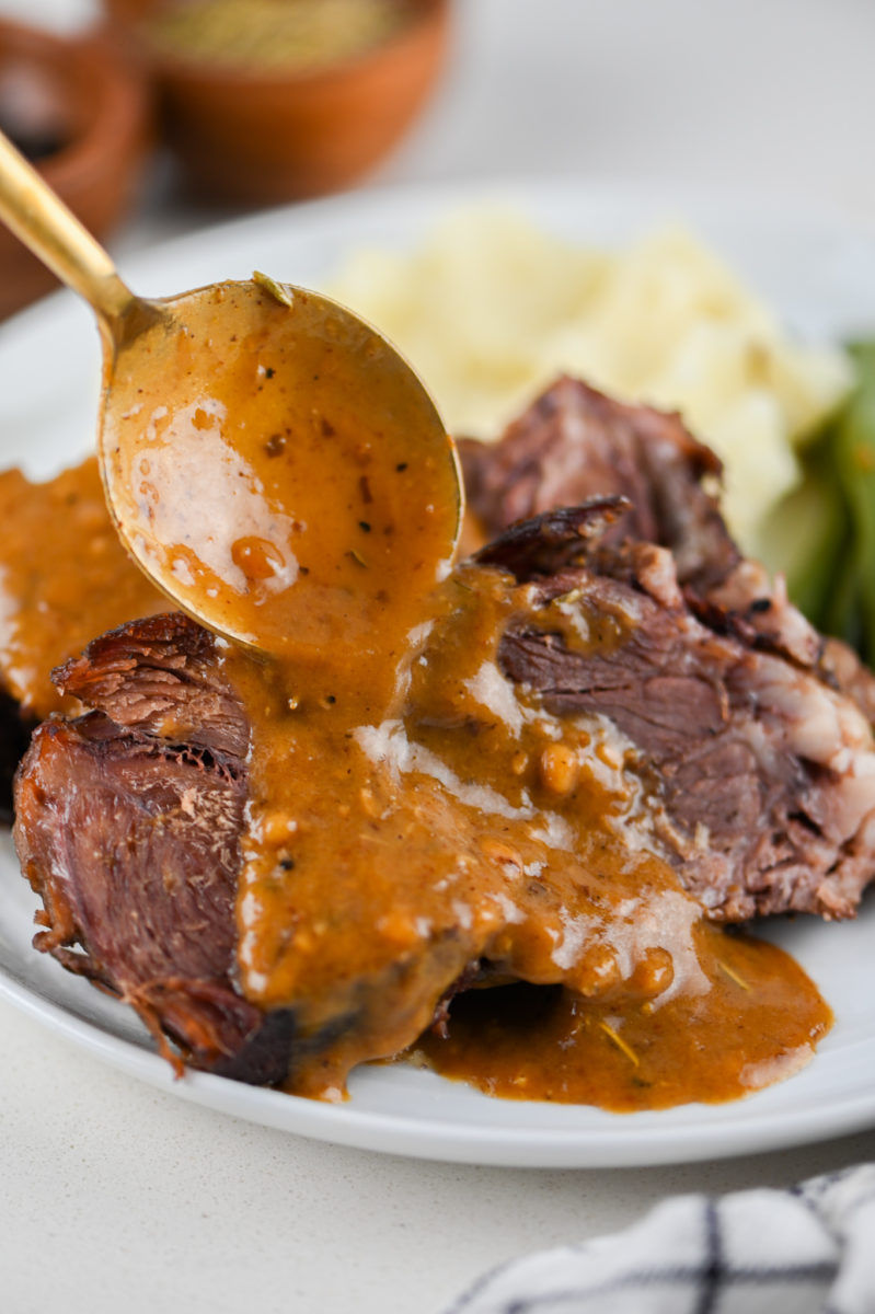 Spoon drizzling rosemary gravy on pot roast. 