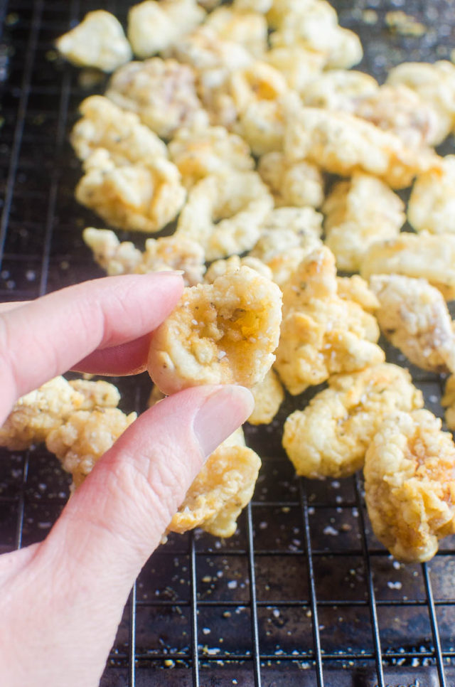 A hand holding fried calamari ring.