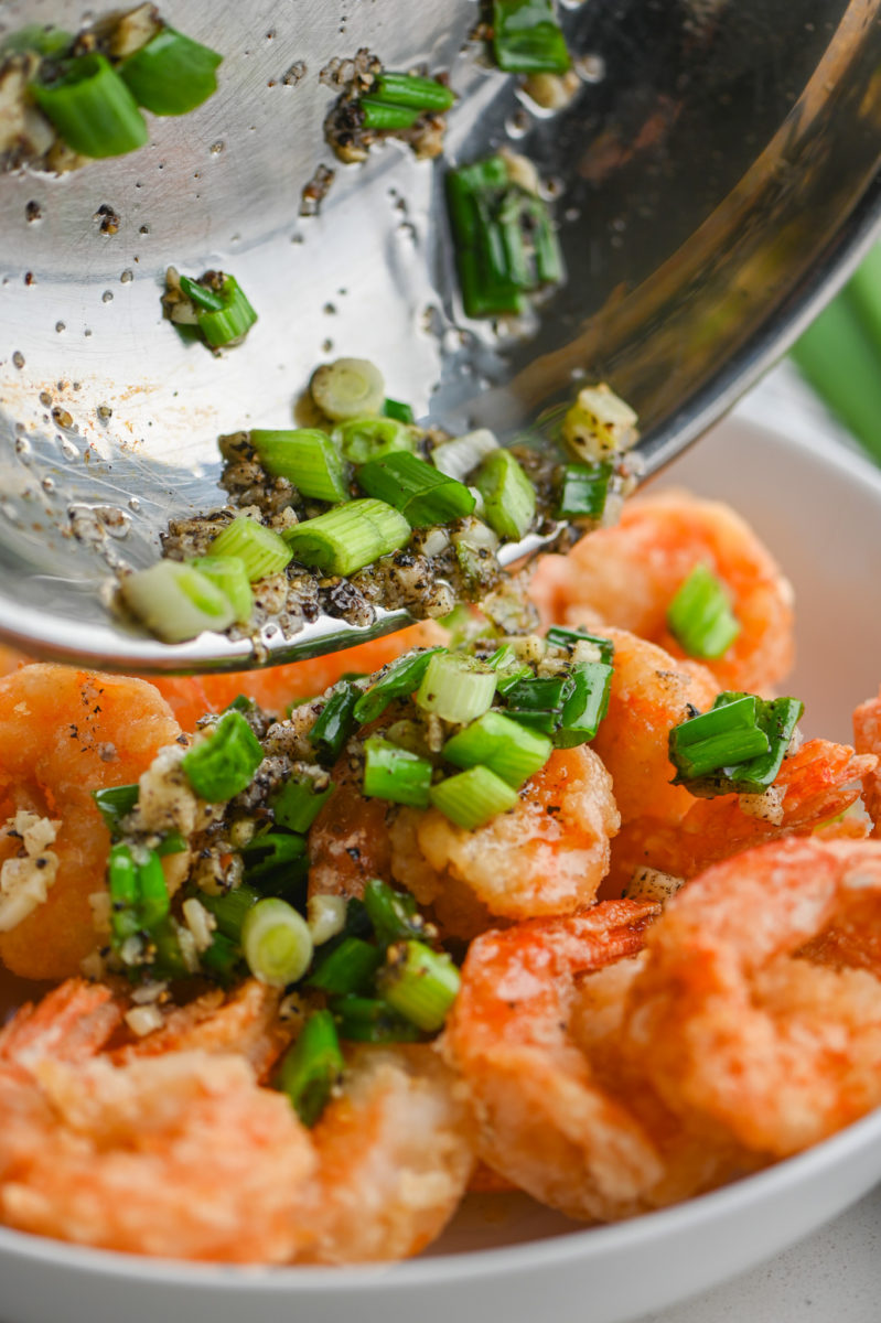 Pouring salt and pepper sauce over shrimp. 