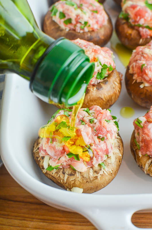 Drizzling olive oil over a stuffed mushroom in a white dish. 