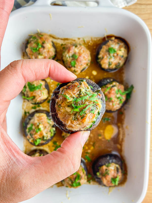 Hand holding a sausage stuffed mushroom